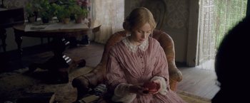 Movie still from “The Invisible Woman” (2013), directed by Ralph Fiennes – A woman in a pink dress sitting in a chair holding an object; Medium shot, High angle