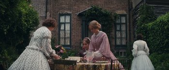 Movie still from “The Invisible Woman” (2013), directed by Ralph Fiennes – Two women and a little girl standing at a table; Wide shot, High angle