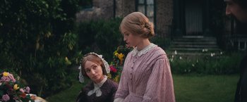 Movie still from “The Invisible Woman” (2013), directed by Ralph Fiennes – Two young women dressed in period clothing standing next to each other; Medium shot, Over the shoulder angle