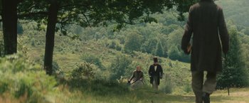 Movie still from “The Invisible Woman” (2013), directed by Ralph Fiennes – Two people in a field with trees in the background; Extreme Wide shot, High angle