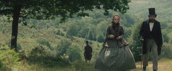 Movie still from “The Invisible Woman” (2013), directed by Ralph Fiennes – A woman standing in front of a man on a hill; Wide shot, Low angle