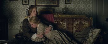 Movie still from “The Invisible Woman” (2013), directed by Ralph Fiennes – Two women sitting on a couch in a living room; Medium shot, High angle