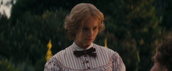 Movie still from “The Invisible Woman” (2013), directed by Ralph Fiennes – A woman in a striped dress and a bow tie; Close Up shot, Over the shoulder angle