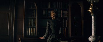 Movie still from “The Invisible Woman” (2013), directed by Ralph Fiennes – A woman standing in front of a book shelf; Medium shot, Low angle