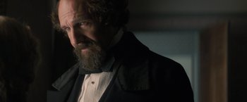 Movie still from “The Invisible Woman” (2013), directed by Ralph Fiennes – A man with a long beard wearing a suit and tie; Close Up shot, Over the shoulder angle