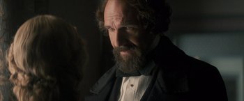 Movie still from “The Invisible Woman” (2013), directed by Ralph Fiennes – A man with long hair and a goatee is looking at the camera; Close Up shot, Over the shoulder angle
