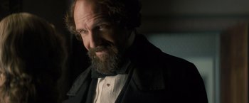 Movie still from “The Invisible Woman” (2013), directed by Ralph Fiennes – A man with a long beard wearing a suit and bow tie; Close Up shot, Over the shoulder angle