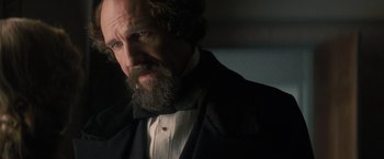 Movie still from “The Invisible Woman” (2013), directed by Ralph Fiennes – A man with a long beard wearing a suit and bow tie; Close Up shot, Over the shoulder angle