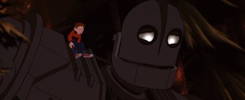 Movie still from “The Iron Giant” (1999), directed by Brad Bird – A boy sitting in front of an iron giant; Medium shot, Low angle