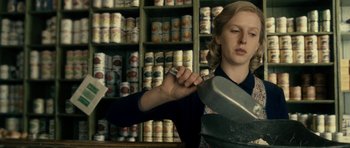 Movie still from “The Iron Lady” (2011), directed by Phyllida Lloyd – A woman is holding a pan in a store; Medium shot, Low angle