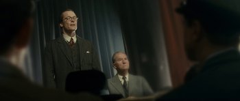 Movie still from “The Iron Lady” (2011), directed by Phyllida Lloyd – Two men in suits and ties sitting in front of a curtain; Medium shot, Low angle