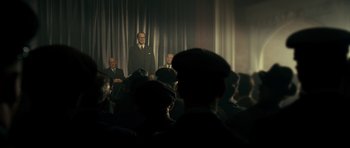 Movie still from “The Iron Lady” (2011), directed by Phyllida Lloyd – A group of men sitting in front of a curtain; Wide shot, Low angle