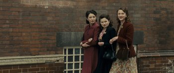 Movie still from “The Iron Lady” (2011), directed by Phyllida Lloyd – A group of women standing next to a brick wall; Medium shot, Low angle