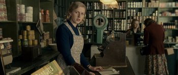 Movie still from “The Iron Lady” (2011), directed by Phyllida Lloyd – A woman standing behind a counter in a store; Medium shot, Over the shoulder angle