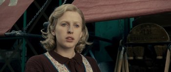 Movie still from “The Iron Lady” (2011), directed by Phyllida Lloyd – A woman with blonde curly hair and a brown dress; Close Up shot, Low angle