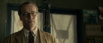 Movie still from “The Iron Lady” (2011), directed by Phyllida Lloyd – A man in a suit and tie standing in front of a window; Close Up shot, Low angle