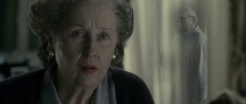 Movie still from “The Iron Lady” (2011), directed by Phyllida Lloyd – An older woman with blue eyes looking at the camera; Close Up shot, Over the shoulder angle