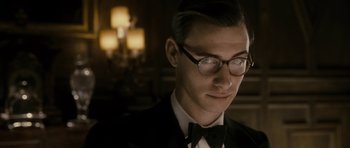 Movie still from “The Iron Lady” (2011), directed by Phyllida Lloyd – A man in a suit and bow - tie wearing glasses; Close Up shot, Low angle