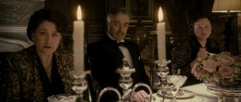 Movie still from “The Iron Lady” (2011), directed by Phyllida Lloyd – A man sitting at a dinner table in front of candles; Medium shot, Low angle