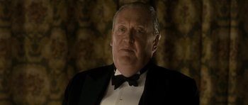 Movie still from “The Iron Lady” (2011), directed by Phyllida Lloyd – An older man wearing a tuxedo and a bow tie; Close Up shot, Low angle