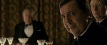 Movie still from “The Iron Lady” (2011), directed by Phyllida Lloyd – A person sitting at a table with a drink; Close Up shot, Over the shoulder angle