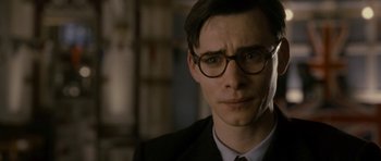 Movie still from “The Iron Lady” (2011), directed by Phyllida Lloyd – A person wearing glasses and a suit; Close Up shot, Over the shoulder angle