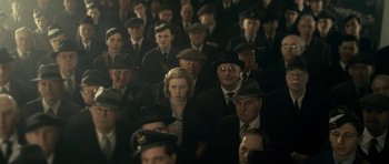 Movie still from “The Iron Lady” (2011), directed by Phyllida Lloyd – A crowd of people in suits and hats; Medium shot, High angle