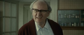 Movie still from “The Iron Lady” (2011), directed by Phyllida Lloyd – An older man with glasses and a beard; Close Up shot, Over the shoulder angle