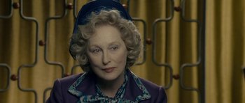 Movie still from “The Iron Lady” (2011), directed by Phyllida Lloyd – An older woman wearing a blue hat and a purple jacket; Close Up shot, Over the shoulder angle