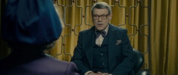 Movie still from “The Iron Lady” (2011), directed by Phyllida Lloyd – An older man wearing a suit and tie talking to an older woman; Medium shot, Over the shoulder angle