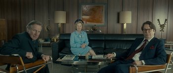 Movie still from “The Iron Lady” (2011), directed by Phyllida Lloyd – An older woman sitting on a black leather couch in a living room; Wide shot, Over the shoulder angle