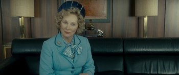 Movie still from “The Iron Lady” (2011), directed by Phyllida Lloyd – An older woman wearing a blue suit and hat; Medium shot, Over the shoulder angle