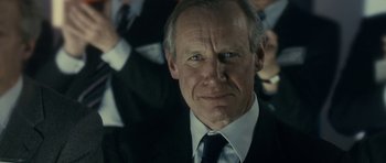 Movie still from “The Iron Lady” (2011), directed by Phyllida Lloyd – An older man wearing a suit and tie; Close Up shot, Over the shoulder angle