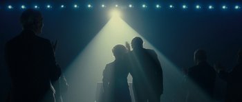 Movie still from “The Iron Lady” (2011), directed by Phyllida Lloyd – Two people standing under a spotlight on a stage; Wide shot, Low angle