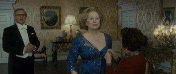 Movie still from “The Iron Lady” (2011), directed by Phyllida Lloyd – An older woman helping a woman with a dress; Medium shot, Over the shoulder angle