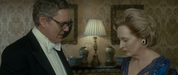 Movie still from “The Iron Lady” (2011), directed by Phyllida Lloyd – A man and a woman standing next to each other in a room; Close Up shot, Over the shoulder angle