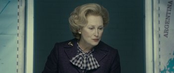 Movie still from “The Iron Lady” (2011), directed by Phyllida Lloyd – An older woman wearing a blue jacket and a checkered neck tie; Close Up shot, Low angle