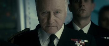 Movie still from “The Iron Lady” (2011), directed by Phyllida Lloyd – An older man wearing a suit and tie; Close Up shot, Over the shoulder angle