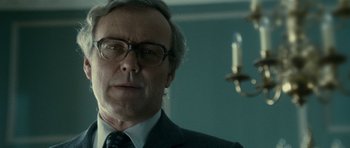 Movie still from “The Iron Lady” (2011), directed by Phyllida Lloyd – An older man in a suit and tie; Close Up shot, Low angle