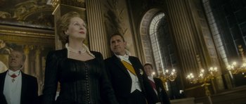 Movie still from “The Iron Lady” (2011), directed by Phyllida Lloyd – A man and two women standing in front of a building; Medium shot, Low angle