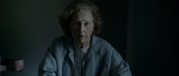 Movie still from “The Iron Lady” (2011), directed by Phyllida Lloyd – An older woman is sitting in front of a wall; Close Up shot, Over the shoulder angle