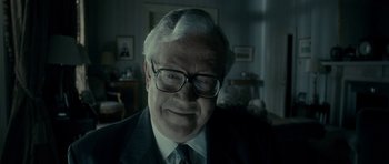 Movie still from “The Iron Lady” (2011), directed by Phyllida Lloyd – An older man wearing glasses and a suit; Close Up shot, Low angle