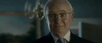 Movie still from “The Iron Lady” (2011), directed by Phyllida Lloyd – An older man wearing glasses and a suit; Close Up shot, Over the shoulder angle