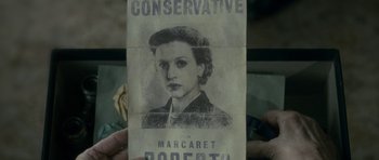 Movie still from “The Iron Lady” (2011), directed by Phyllida Lloyd – A person holding a pamphlet with an image of a woman; Close Up shot, Overhead angle