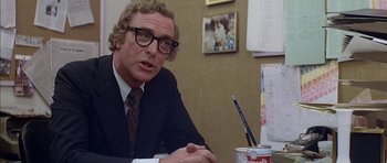 Movie still from “The Island” (1980), directed by Michael Ritchie – A man sitting at a table in front of a cup of coffee; Close Up shot, Over the shoulder angle