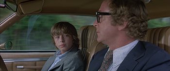 Movie still from “The Island” (1980), directed by Michael Ritchie – A man and a boy sitting in the back seat of a car; Close Up shot, Over the shoulder angle
