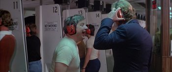 Movie still from “The Island” (1980), directed by Michael Ritchie – A group of people wearing ear muffs in a room; Medium shot, Over the shoulder angle