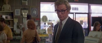 Movie still from “The Island” (1980), directed by Michael Ritchie – A man in a suit and tie standing next to a woman; Close Up shot, Over the shoulder angle