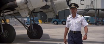 Movie still from “The Island” (1980), directed by Michael Ritchie – A man in a uniform walking in front of an airplane; Medium shot, Low angle