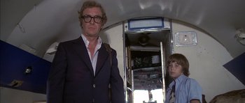 Movie still from “The Island” (1980), directed by Michael Ritchie – A man standing next to a young boy in front of an elevator; Medium shot, Low angle